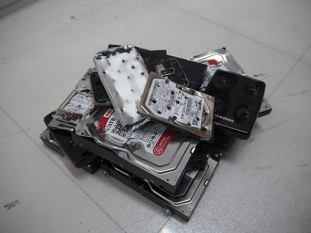 4点圧壊処理を行った破壊後のHDD。筐体に圧痕が入り内部プラッタが変形している